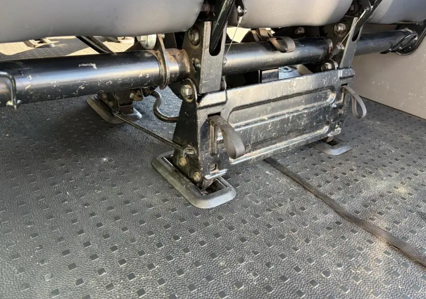 Gros plan sous les sièges arrière du Volkswagen Transporter T6 Minibus blanc, montrant la fixation et la structure métallique.
