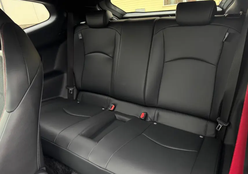 Vue intérieure de la banquette arrière en cuir noir de la Toyota Yaris GR avec ceintures de sécurité et surpiqûres rouges.
