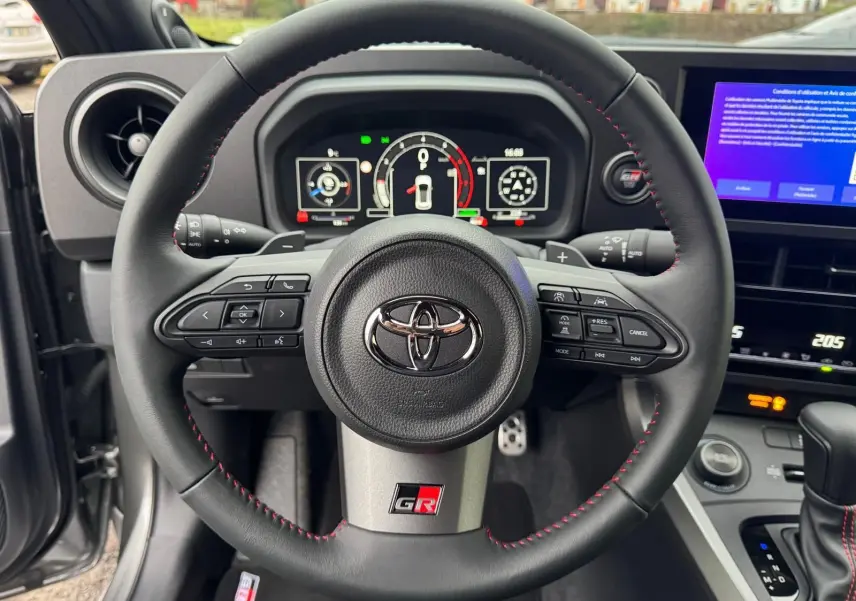 Vue rapprochée du volant noir avec surpiqûres rouges et logo GR de la Toyota Yaris GR Pack Techno.