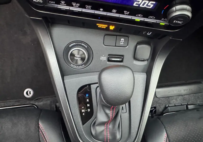 Gros plan sur la console centrale de la Toyota Yaris GR avec levier de vitesses et surpiqûres rouges visibles.