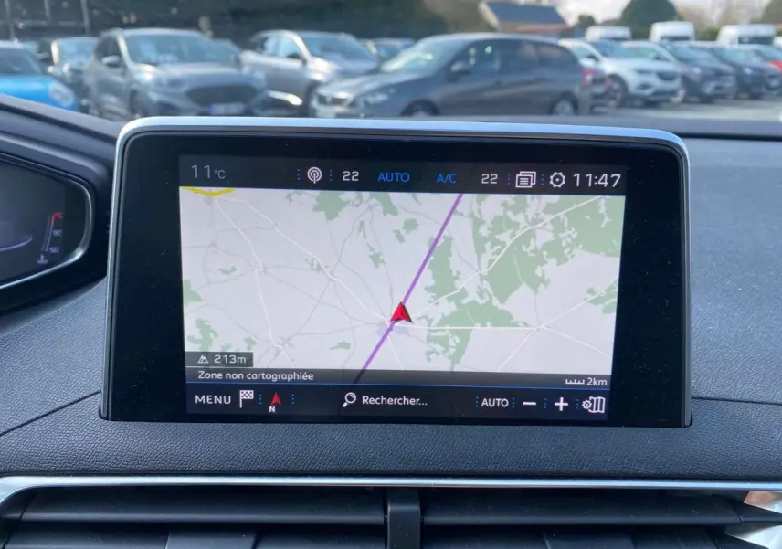 Écran central du tableau de bord du Peugeot 3008 blanc, affichant la navigation GPS en extérieur.