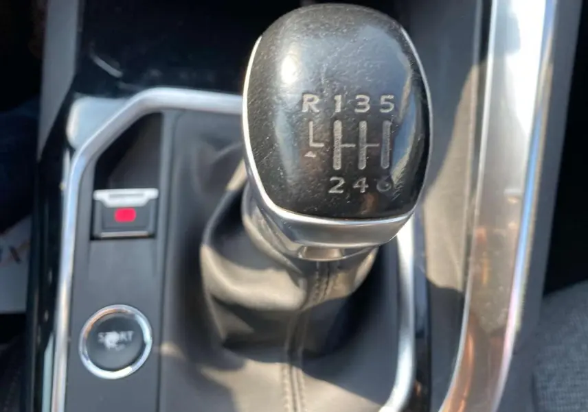Gros plan sur le levier de vitesses manuelle noir du Peugeot 3008 blanc, avec bouton mode Sport visible à gauche.