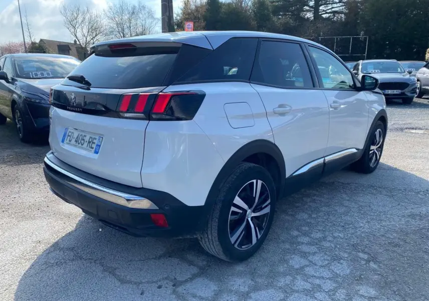 Vue 3/4 arrière droite d'un Peugeot 3008 blanc avec feux arrière à trois griffes et vitres surteintées.