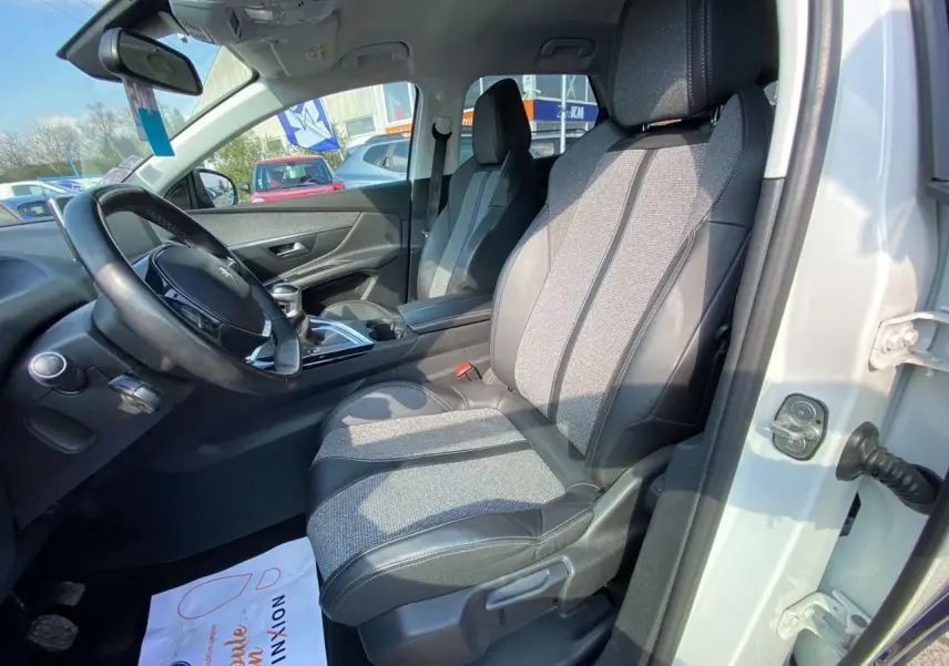 Vue intérieure côté conducteur du Peugeot 3008 blanc, montrant les sièges bi-matière et le volant multifonction.