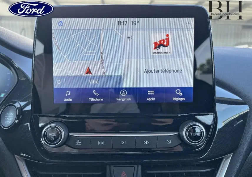 Vue rapprochée de l’écran tactile central et des commandes audio d’un Ford Puma gris Solar métallisé, intérieur noir brillant.