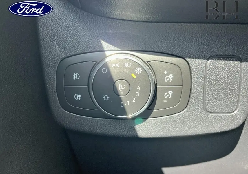 Gros plan sur la molette de réglage des phares du tableau de bord d’un Ford Puma gris Solar Métallisé.