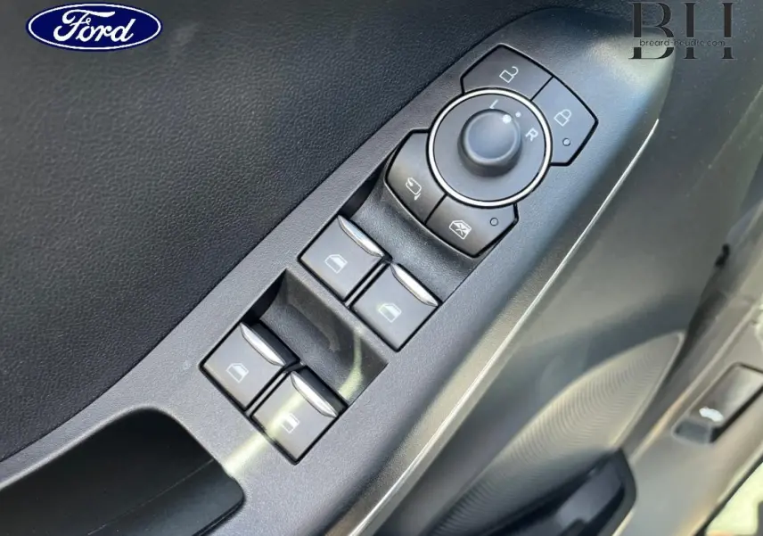 Gros plan sur les commandes des vitres et rétroviseurs côté conducteur d'une Ford Puma 2022 gris Solar métallisé.