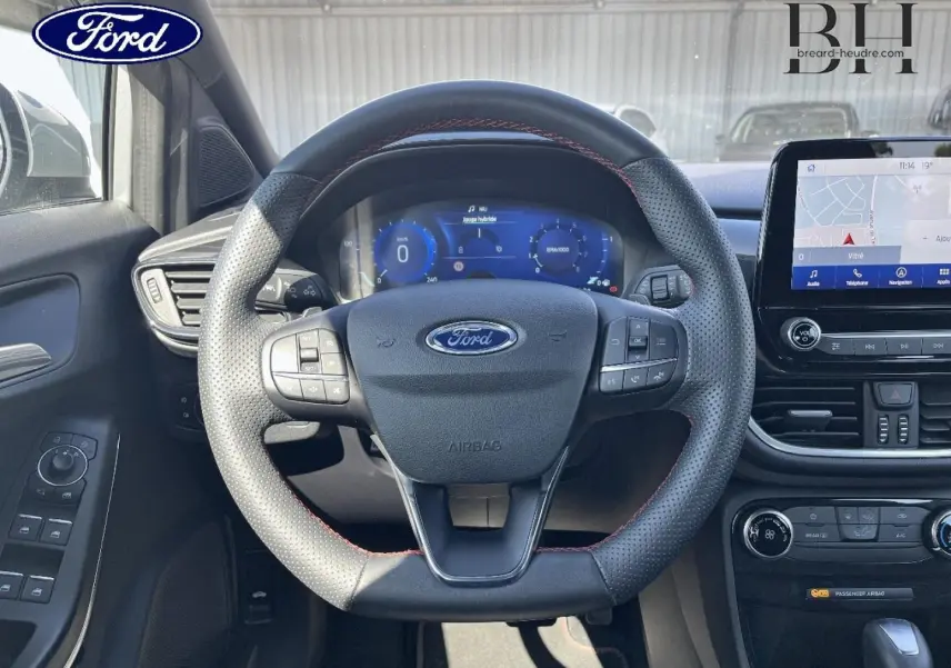 Vue intérieure centrée sur le volant sport perforé avec surpiqûres rouges du Ford Puma 2022, écran tactile et tableau de bord numérique.