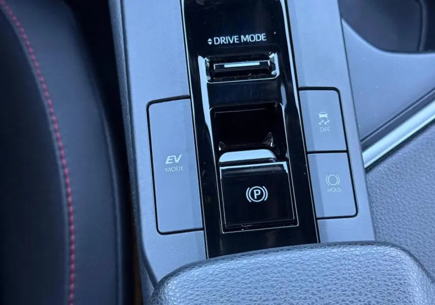 Gros plan sur la console centrale du Toyota C-HR 2025, boutons EV Mode, Drive Mode et frein à main électronique.