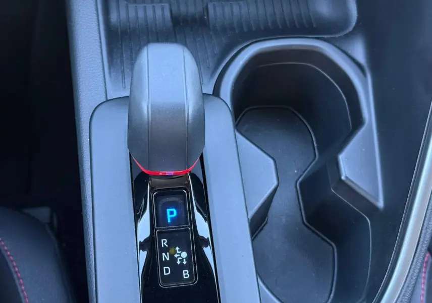 Gros plan sur la console centrale du Toyota C-HR 2.0 Hybride 200ch GR Sport, levier de vitesse et porte-gobelets noirs.