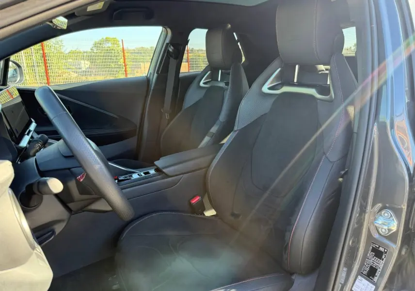 Vue intérieure côté conducteur du Toyota C-HR 2.0 Hybride GR Sport 2025 avec sièges sport noirs et surpiqûres rouges.