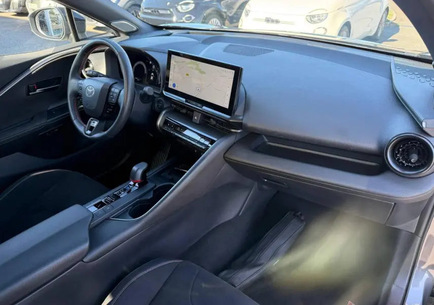 Vue intérieure côté conducteur du Toyota C-HR 2.0 Hybride 200ch GR Sport 2025 avec tableau de bord noir et écran tactile GPS.