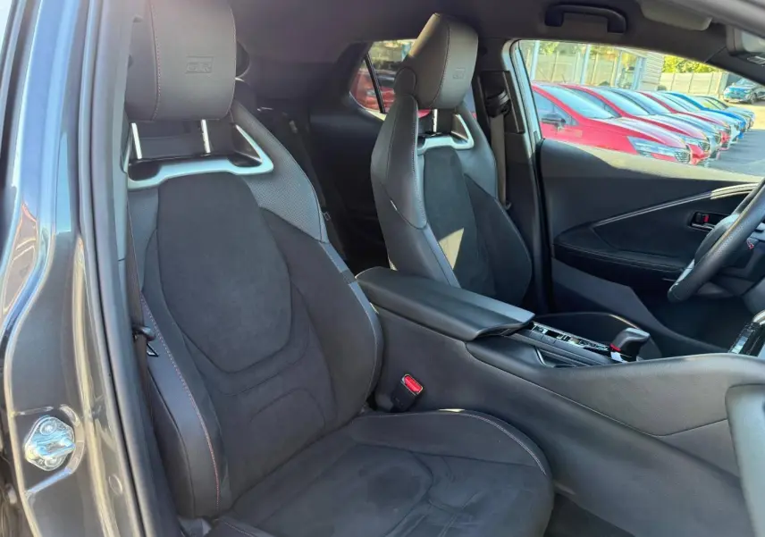 Intérieur avant du Toyota C-HR GR Sport 2025, sièges sport noirs avec logo GR et surpiqûres rouges visibles.