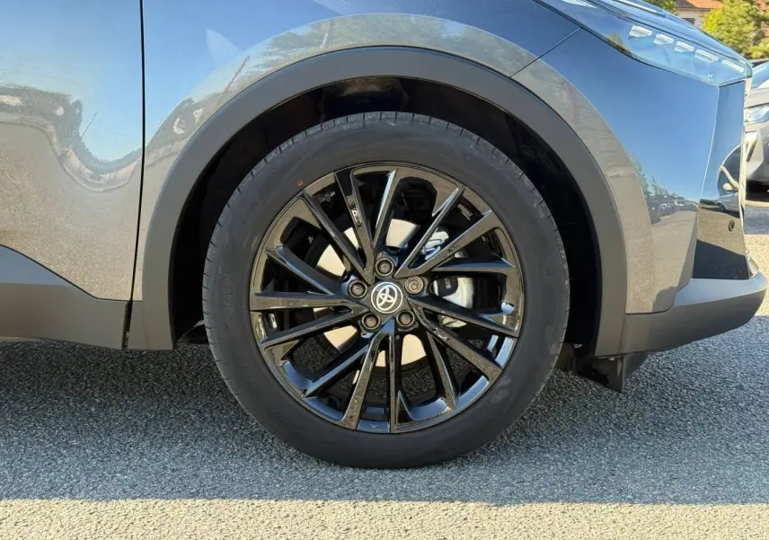 Gros plan sur la roue avant droite avec jante alu noire du Toyota C-HR gris Atlas métallisé bi-ton.