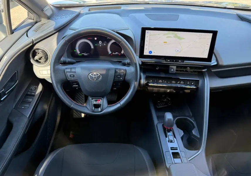 Vue intérieure avant du Toyota C-HR GR Sport 2025, volant sport noir avec logo GR et écran tactile GPS.