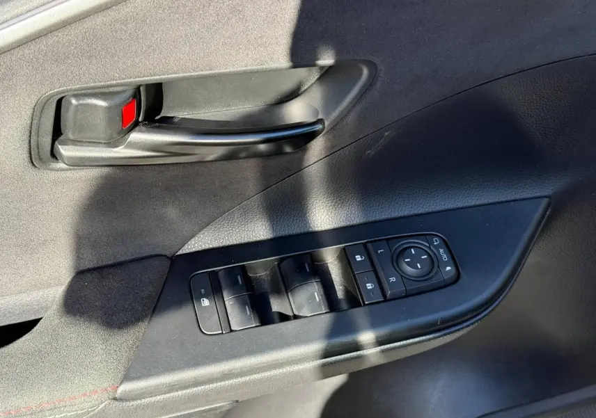Gros plan sur la commande des vitres et la poignée intérieure noire du côté gauche d’une Toyota C-HR gris Atlas bi-ton.
