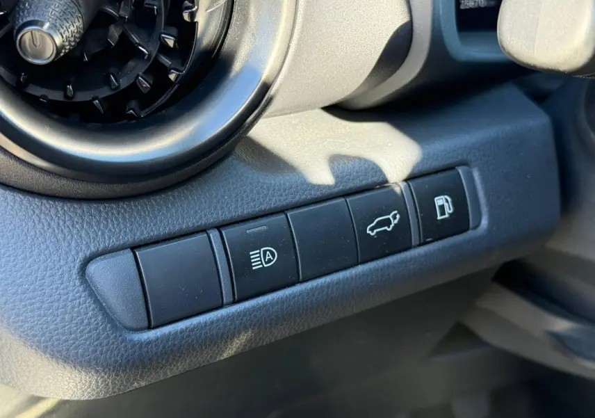 Gros plan sur les boutons de commande noirs à gauche du volant du Toyota C-HR 2.0 Hybride gris Atlas métallisé.