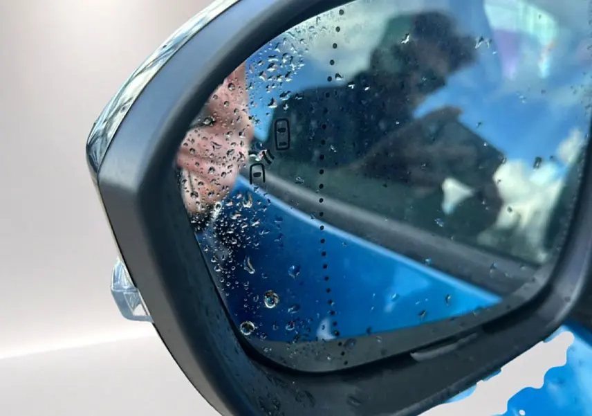 Rétroviseur extérieur côté gauche bleu outremer de Renault Austral 2026 avec gouttes d'eau et détection angle mort.