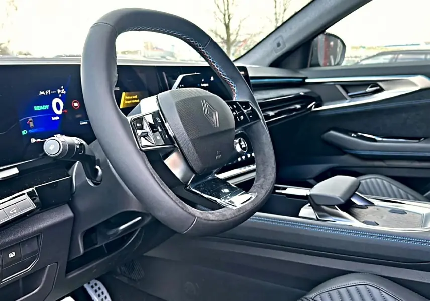 Intérieur avant droit du Renault Austral 2026, volant multifonction noir avec surpiqûres bleues et tableau de bord digital.