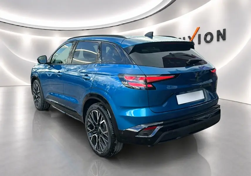 Vue 3/4 arrière droite d'un Renault Austral bleu outremer avec jantes alliage et toit noir dans un showroom lumineux.