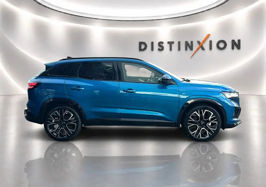 Profil droit du Renault Austral bleu outremer 2026 avec jantes alu noires et toit noir, sur fond lumineux intérieur.