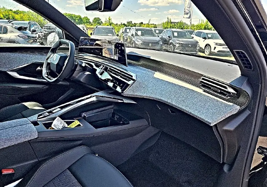 Vue intérieure côté passager du Peugeot 3008 noir 1.2 hybrid 2026, tableau de bord avec habillage tissu gris et écran tactile central.