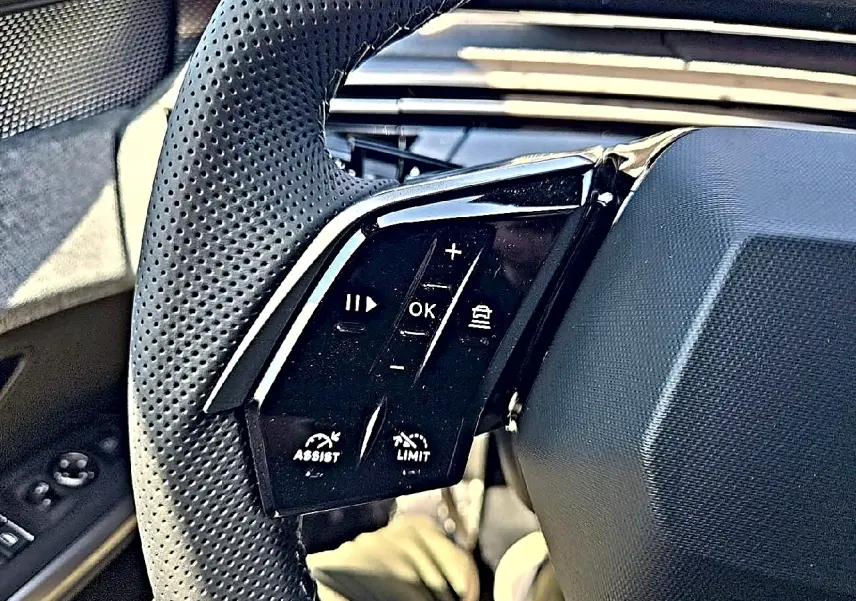 Gros plan sur les commandes gauche du volant cuir perforé du Peugeot 3008 noir, boutons multifonctions visibles.