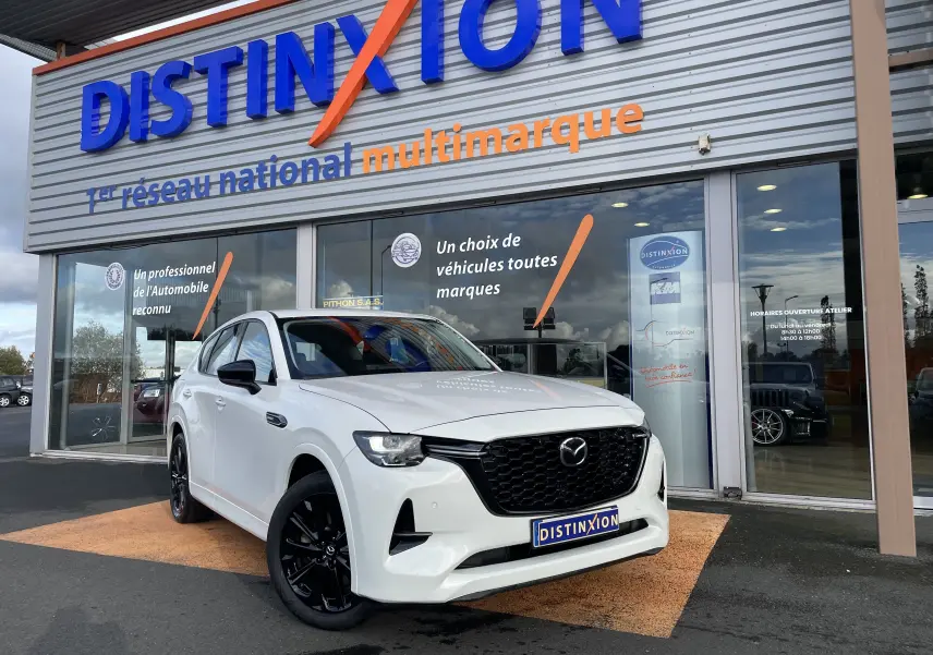Vue 3/4 avant droite d'un Mazda CX-60 blanc nacré avec jantes noires, devant une concession Distinxion.