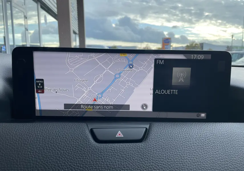 Écran central du tableau de bord du Mazda CX-60 2023 affichant la navigation et la radio FM, vue intérieure frontale.