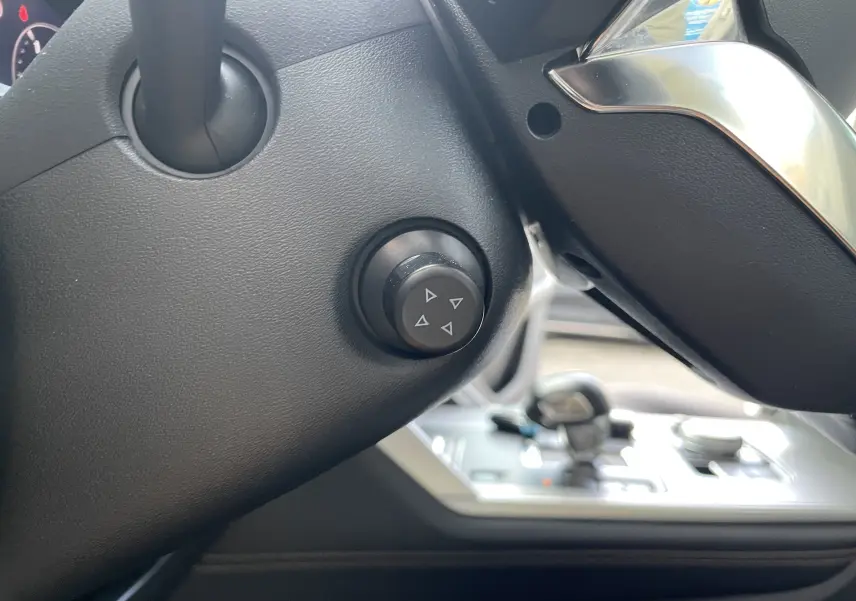 Détail du bouton de réglage sur la colonne de direction noire du Mazda CX-60 2023, intérieur gris-noir.