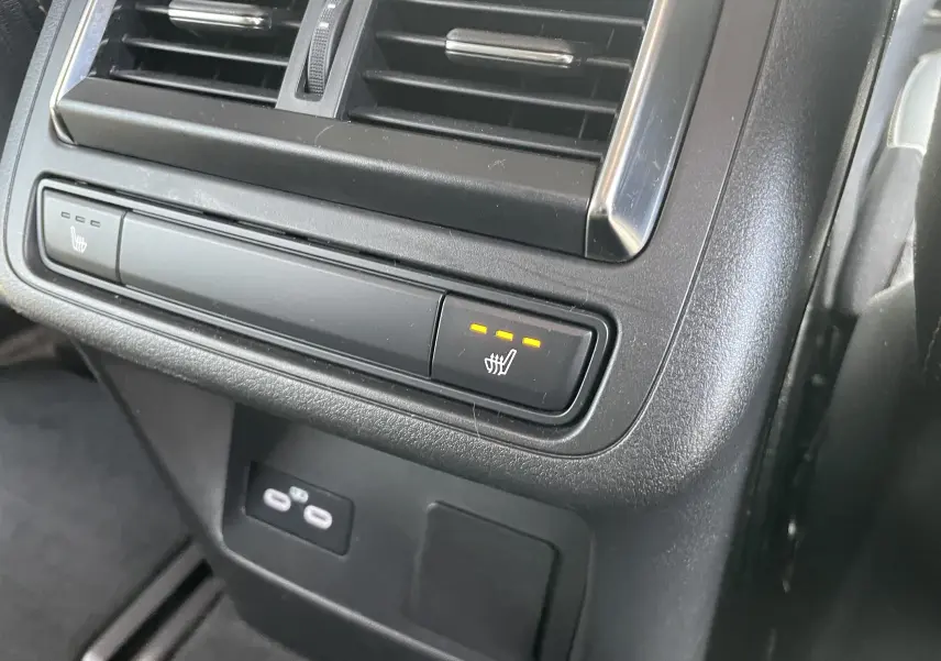 Gros plan sur la commande de siège chauffant arrière droite avec trois voyants orange allumés dans un Mazda CX-60 blanc nacré 2023.