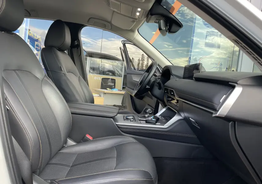 Vue intérieure côté conducteur du Mazda CX-60 blanc nacré 2023, avec sièges cuir noirs et tableau de bord moderne.