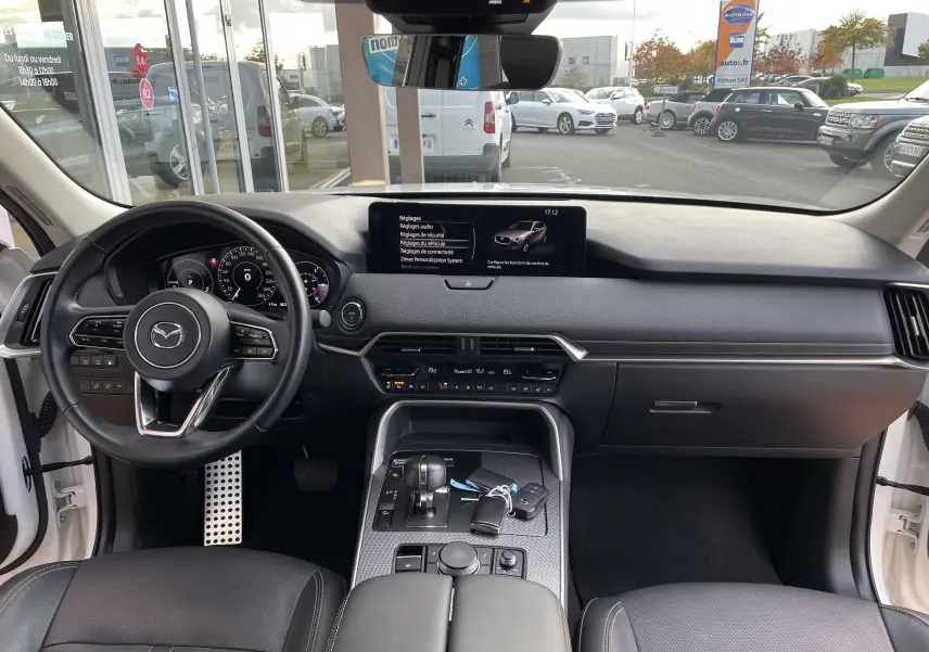 Vue intérieure avant du Mazda CX-60 blanc nacré 2023, tableau de bord moderne avec écran central et volant multifonction.
