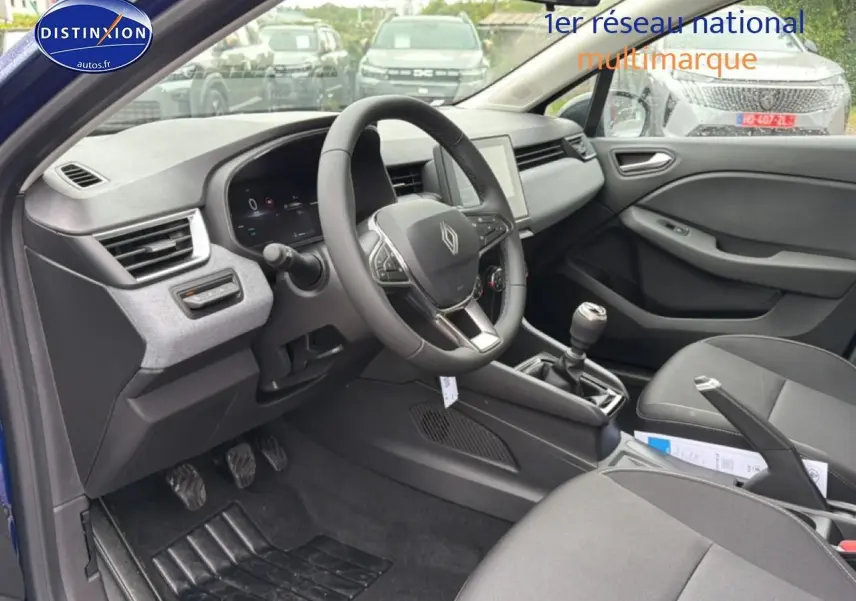 Intérieur avant droit de la Renault Clio V bleu iron, volant multifonction et boîte manuelle visibles.