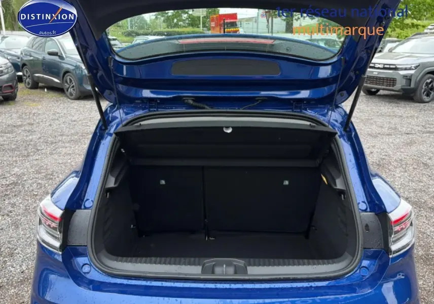 Coffre ouvert vu de l'arrière d'une Renault Clio V bleu iron, montrant l'espace de chargement vide.