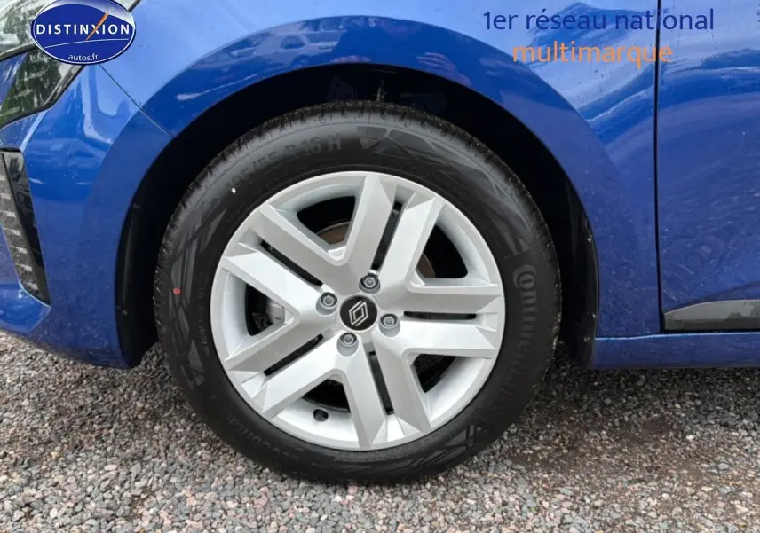Gros plan sur la roue avant gauche d'une Renault Clio V bleu iron avec jante en alliage et logo Renault central.
