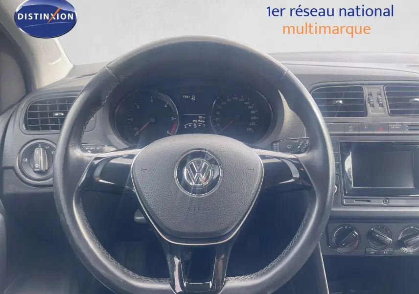 Vue intérieure centrée sur le volant noir d'une Volkswagen Polo 2016 avec tableau de bord et commandes visibles.