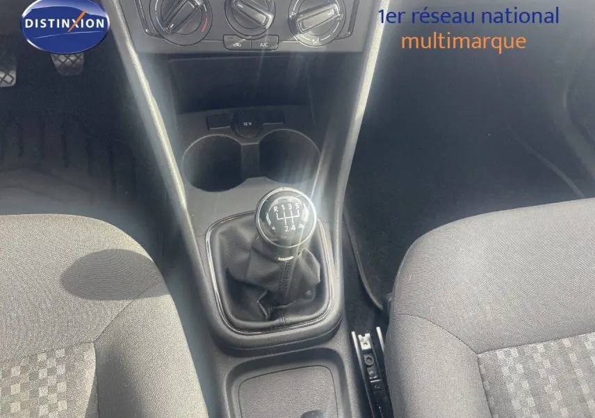 Vue intérieure centrée sur la console centrale d'une Volkswagen Polo noire 2016, mettant en valeur le levier de vitesses manuel.