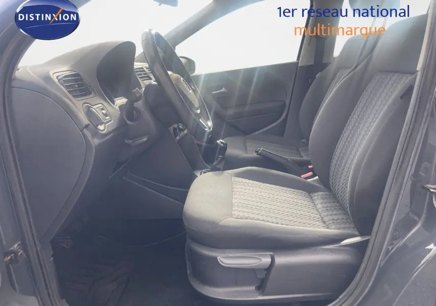 Vue intérieure côté conducteur de la Volkswagen Polo noire 2016, montrant les sièges avant et le volant avec boîte manuelle.