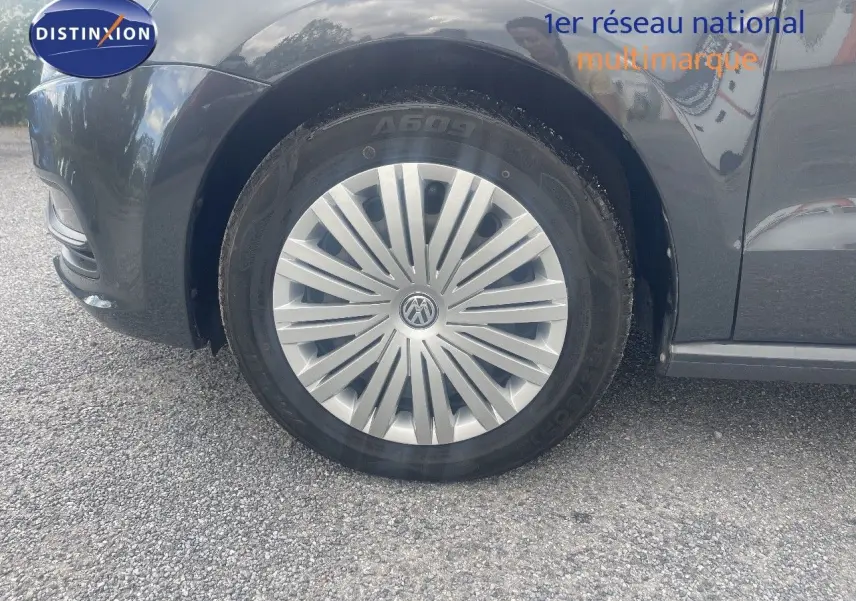 Gros plan sur la roue avant gauche d'une Volkswagen Polo noire de 2016 avec enjoliveur argenté distinctif.