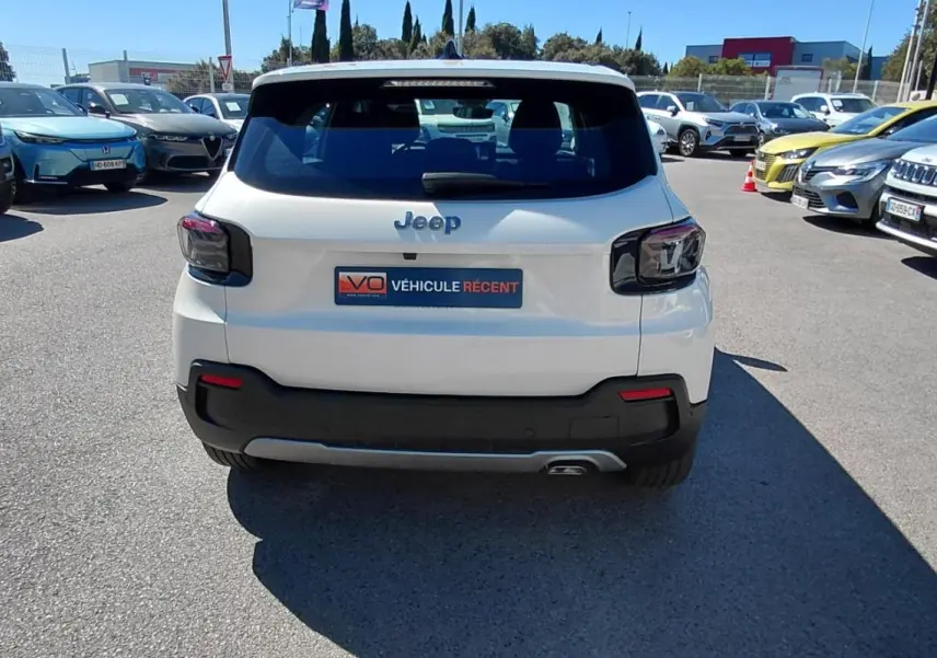 Vue arrière d'un Jeep Avenger blanc 2025 avec feux arrière sombres et plaque "Véhicule récent" sur parking.
