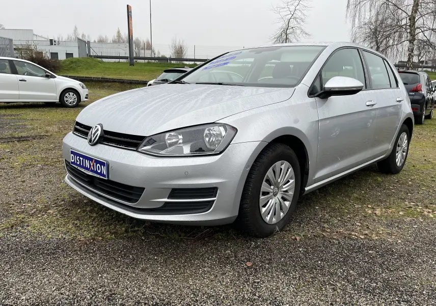Volkswagen Golf 7 argent vue 3/4 avant droit sur parking avec plaque Distinxion visible.