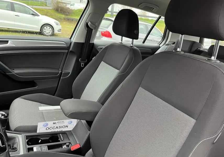 Vue intérieure de la Golf 7 2017 montrant les sièges avant en tissu noir et gris avec accoudoir central.