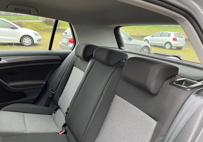 Vue intérieure arrière de la Volkswagen Golf 7 2017, sièges tissu noir et gris, avec appuie-têtes et ceinture visible.