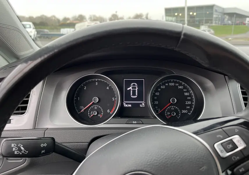 Vue intérieure du tableau de bord d'une Volkswagen Golf 7 argent, avec affichage numérique et volant multifonction noir.