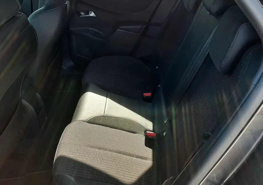 Vue intérieure du siège arrière droit du DS3 Crossback gris foncé, montrant les assises en tissu et cuir noir avec ceinture de sécurité rouge.