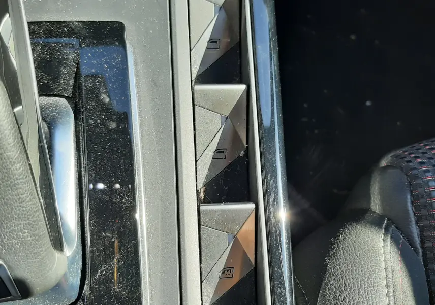 Gros plan sur les commandes de lève-vitres et verrouillage central du DS3 Crossback gris foncé, intérieur cuir noir.