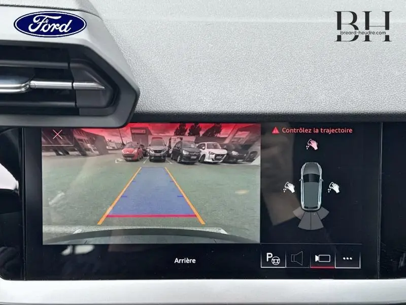 Vue de l'écran de caméra de recul d'une Audi A3 Sportback noire, avec guidage de trajectoire et alertes visibles.