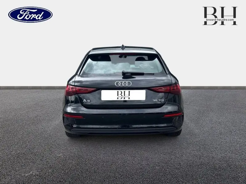 Vue arrière d'une Audi A3 Sportback 35 TDI noire métallisée, avec feux arrière LED et logo Audi visible.