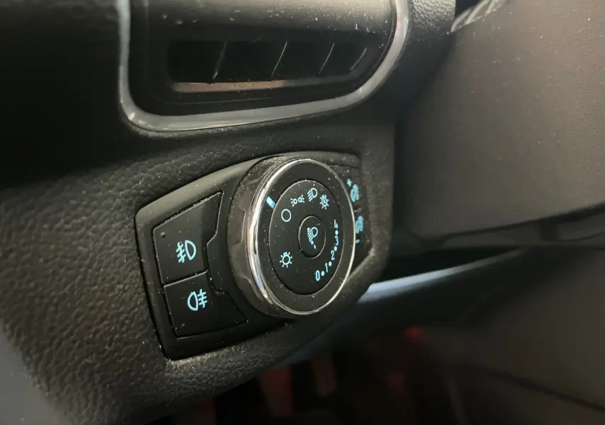 Gros plan sur le bouton de commande des phares et feux antibrouillard dans l’habitacle noir du Ford B-MAX gris clair 2015.
